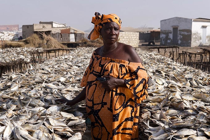 Woman in front of mound of dried fish