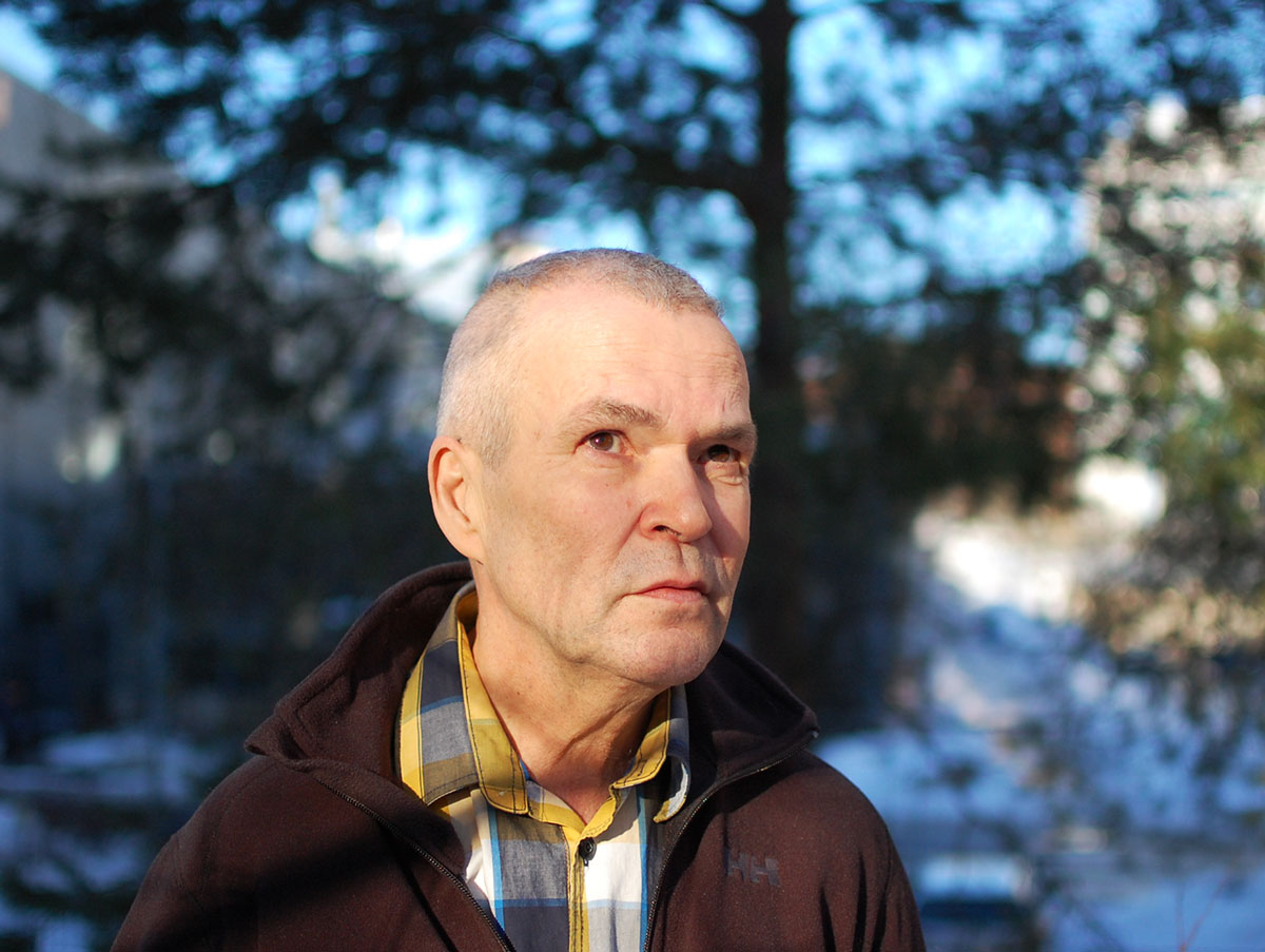 A man outside in front of some pine trees.