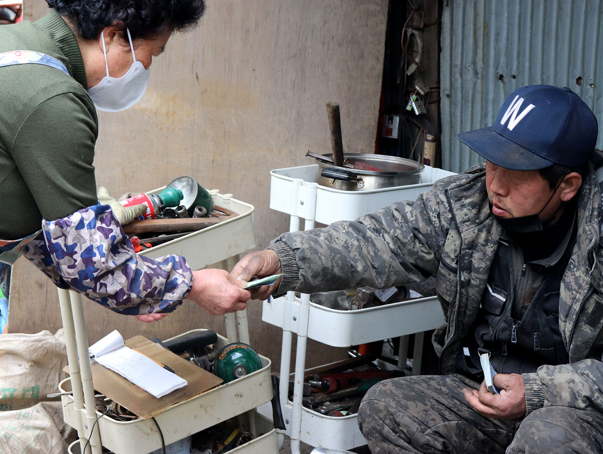 A man handing money over to a woman in exchange for recyclables.