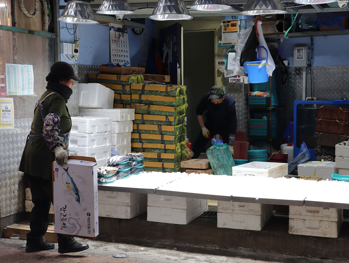 A woman standing in front of a fish vendor's stall.
