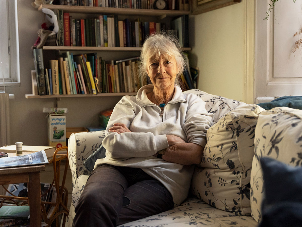 A woman sitting on a white sofa with her arms crossed.