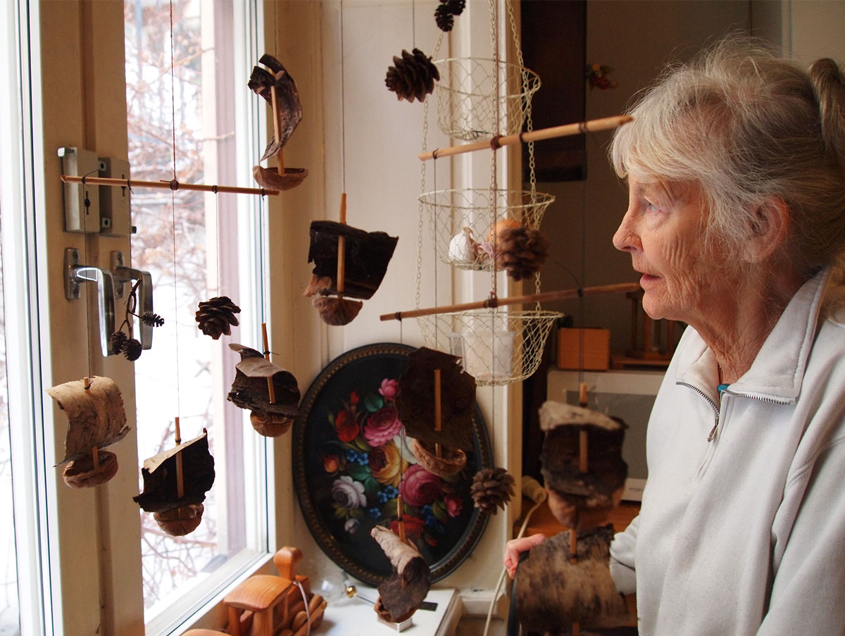 A woman looking out the window with a mobile in front.