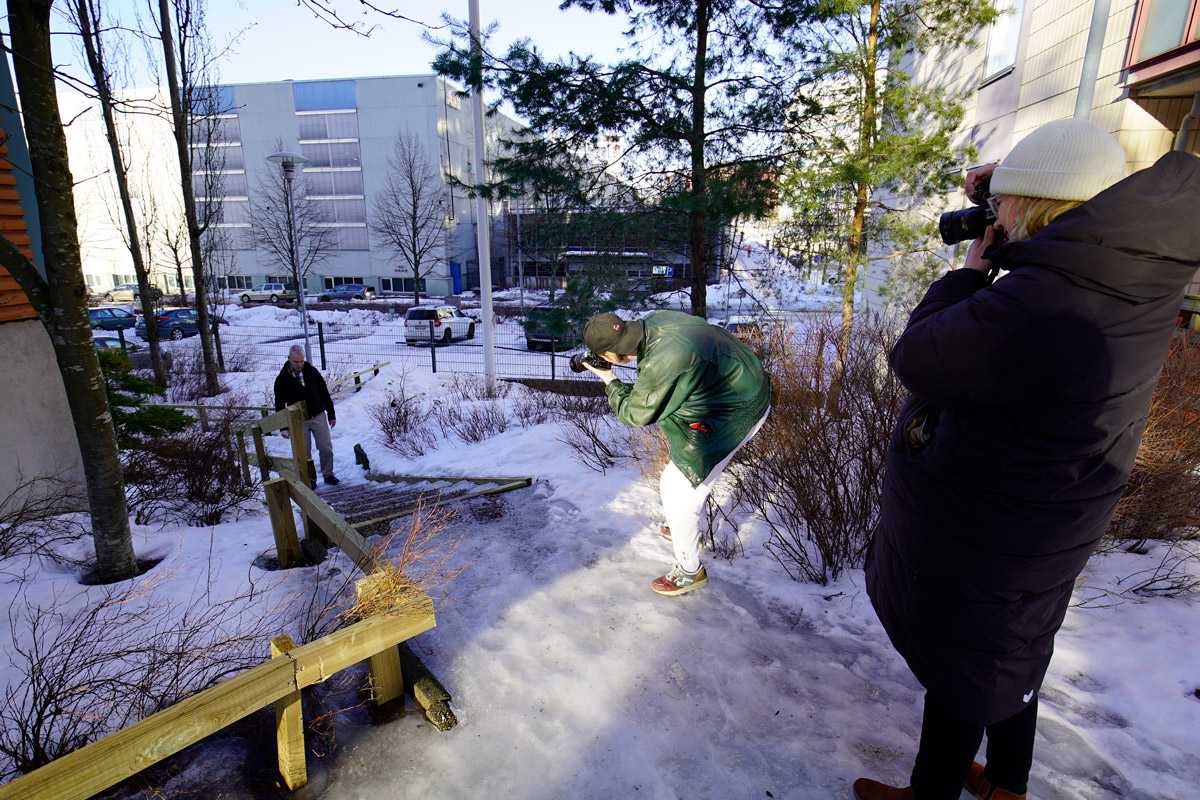 Two people taking photo of a man walking up snow-covered steps in Finland.